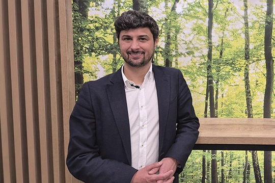 Aurelio posando para la fotografía con un bosque de fondo