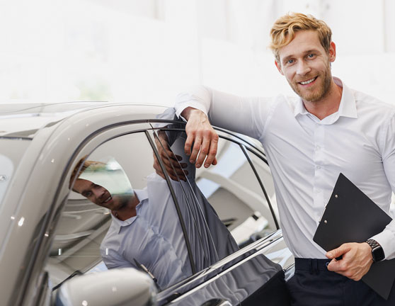 Hombre vendedor de coches mostrando un vehículo en concesionario