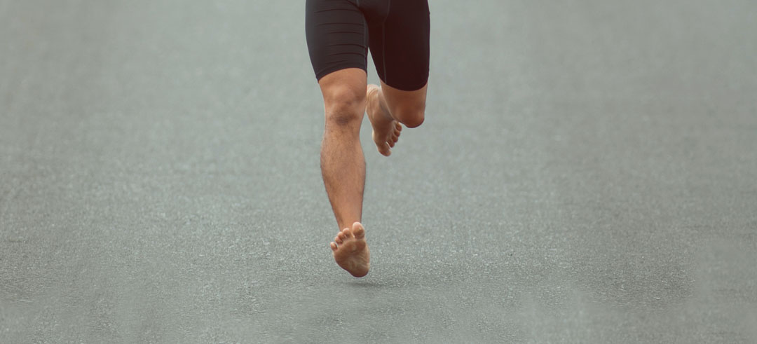 Persona corriendo descalza por una carretera